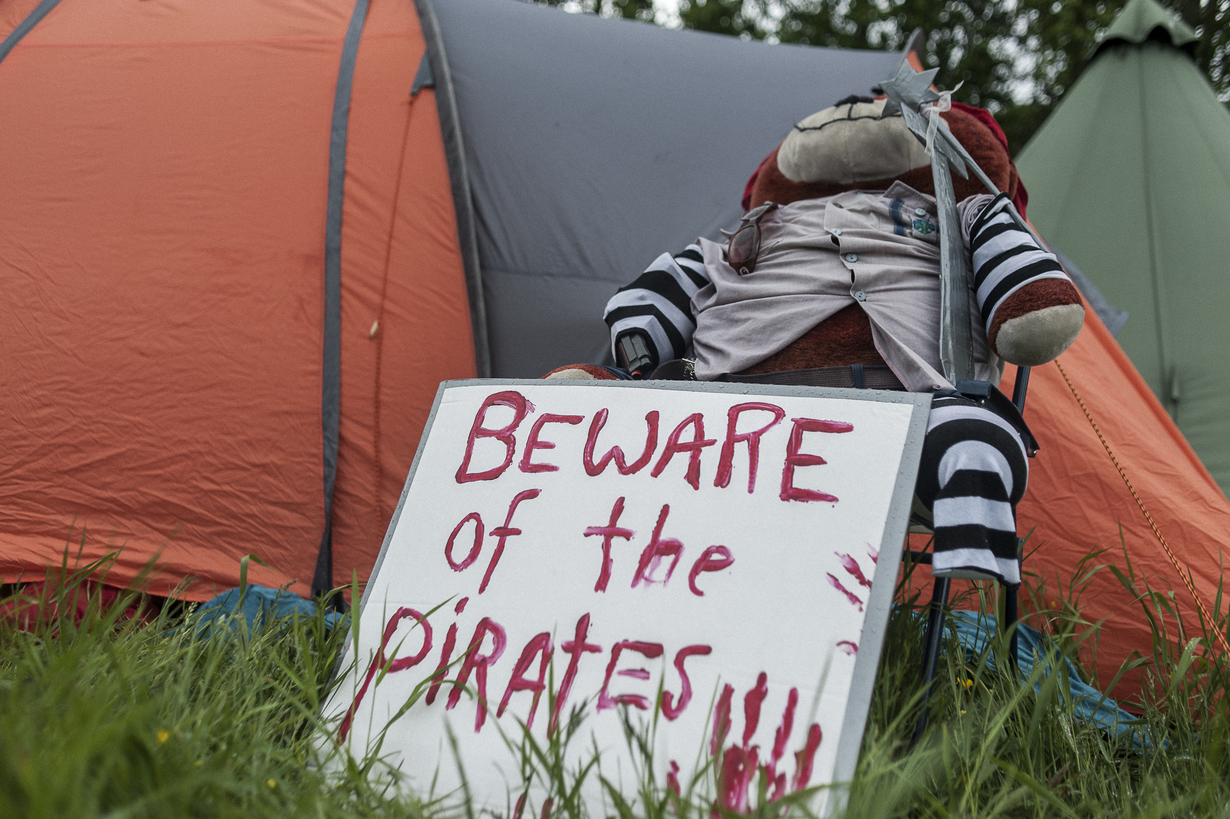 Bamse med piratskilt foran telt på leir