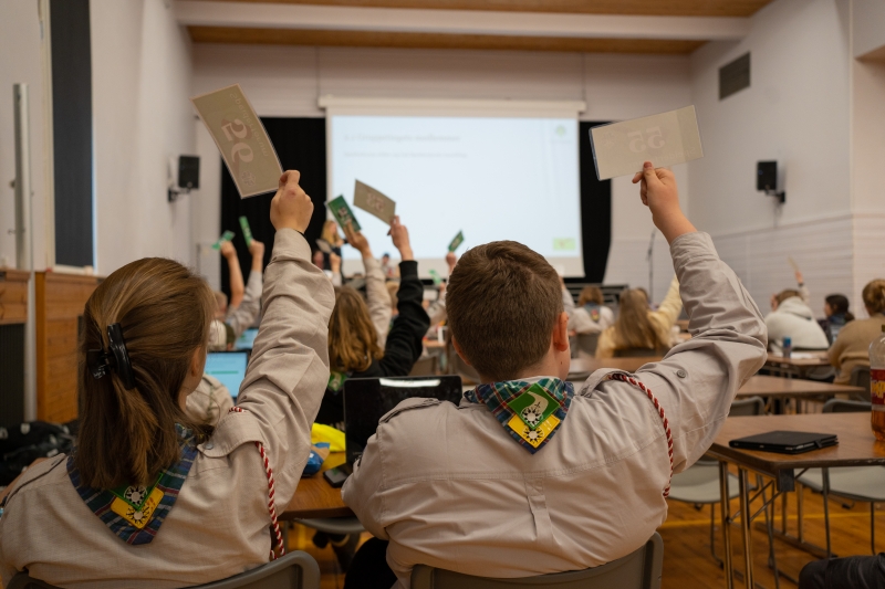 Speidere rekker opp hånden med stemmekort på et møte