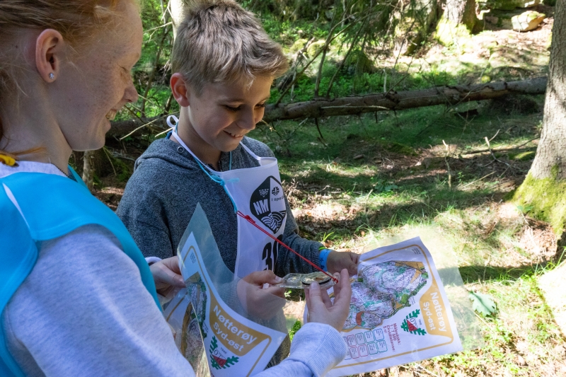 To speidere studerer kart og kompass ute i skogen