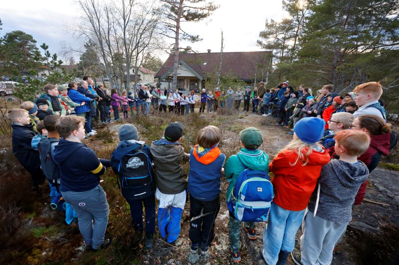Stor gruppe speidere som står i ring ute i naturen og holder hender