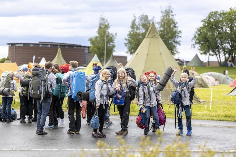 Speidere med sekker og telt i bakgrunnen på leir