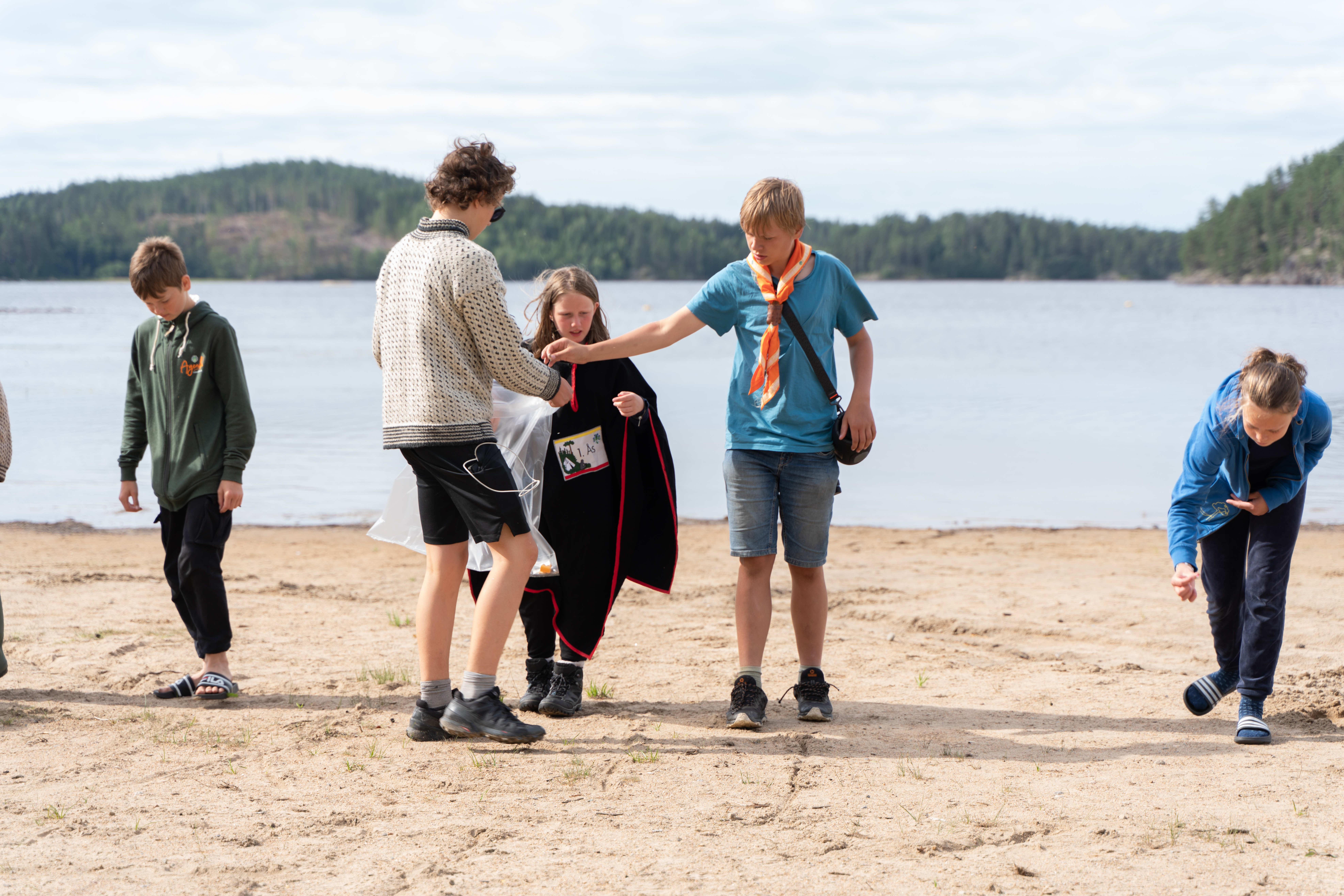 Speidere rydder søppel på en sandstrand ved vannet
