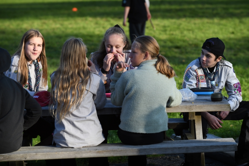 Speidere som sitter rundt et bord og spiser og prater.