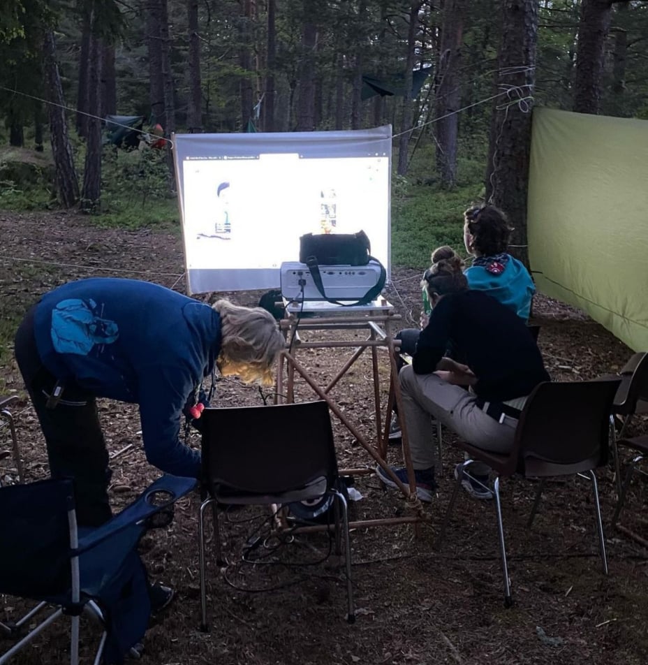 Rovere ser utekino i skogen med projektor og lerret