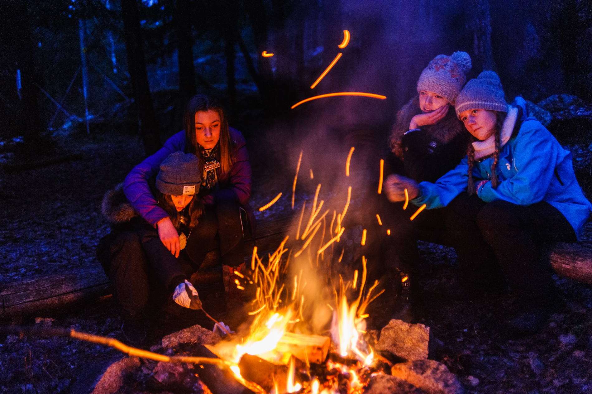 Speidere rundt et bål om kvelden i skogen