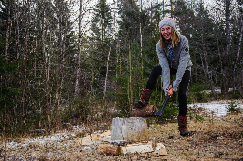 En speider som hugger ved på en huggestabbe i skogen